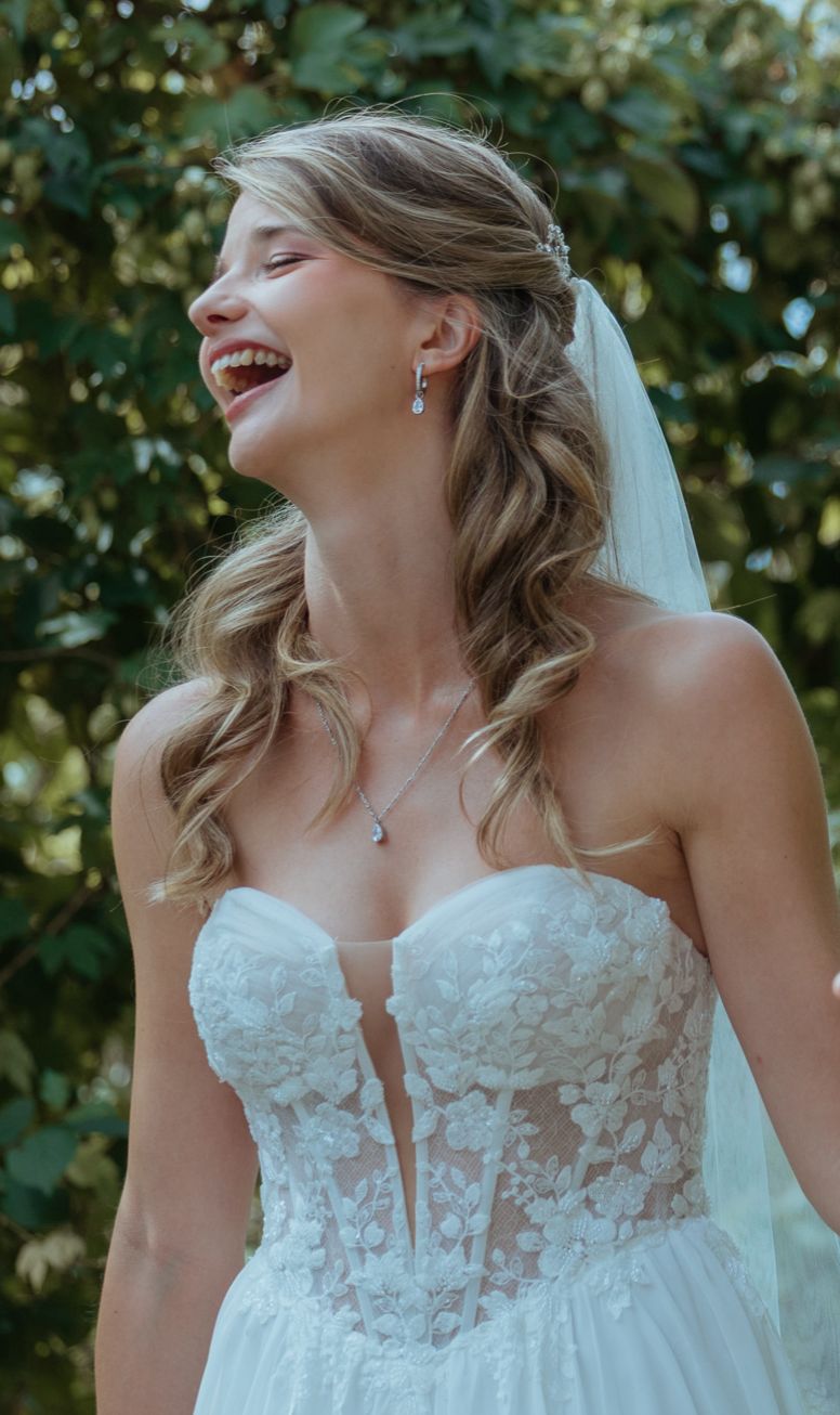 Lachende Braut mit natürlichem Braut Make-up und weichen Wellen
